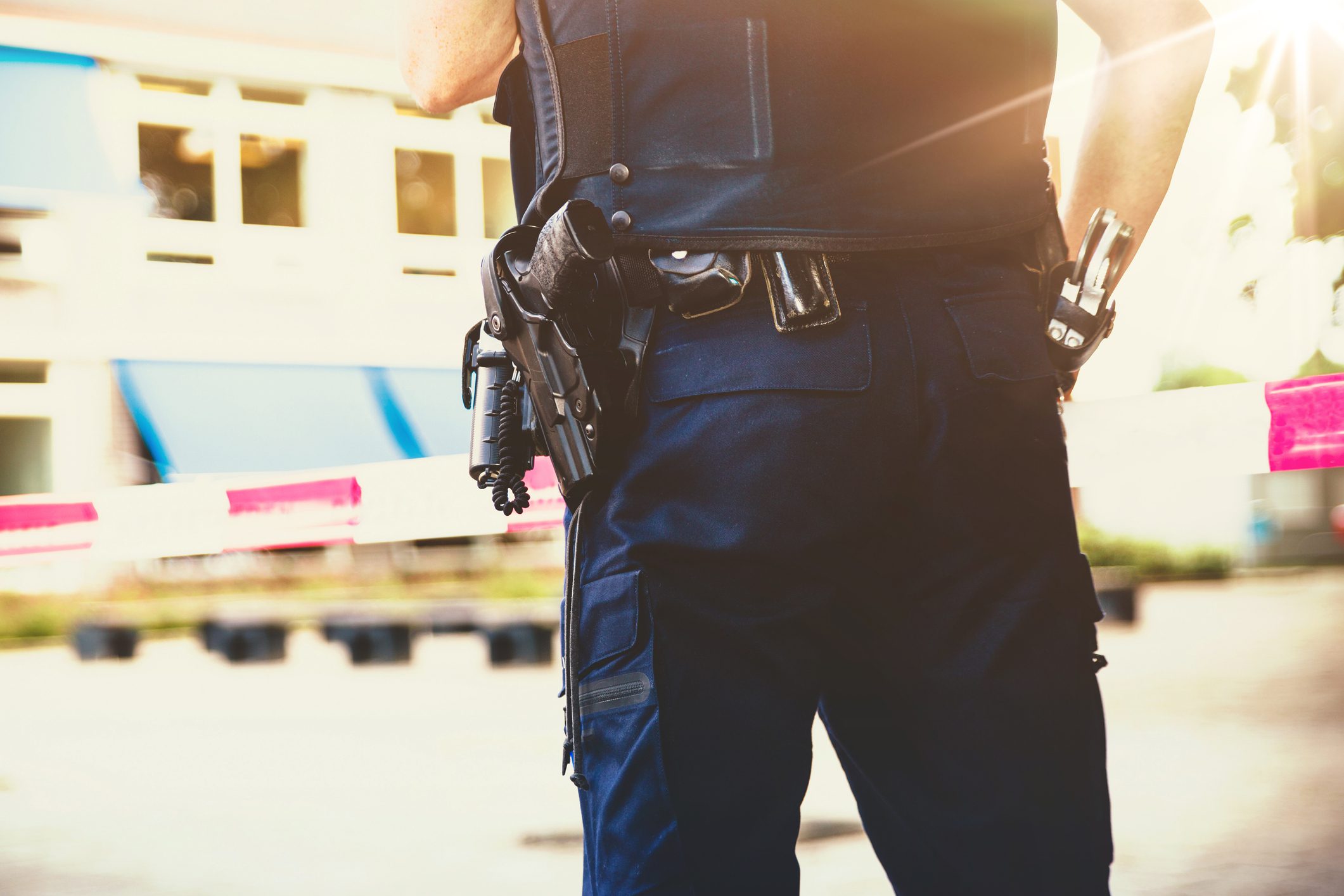 Police officer standing near caution tape.