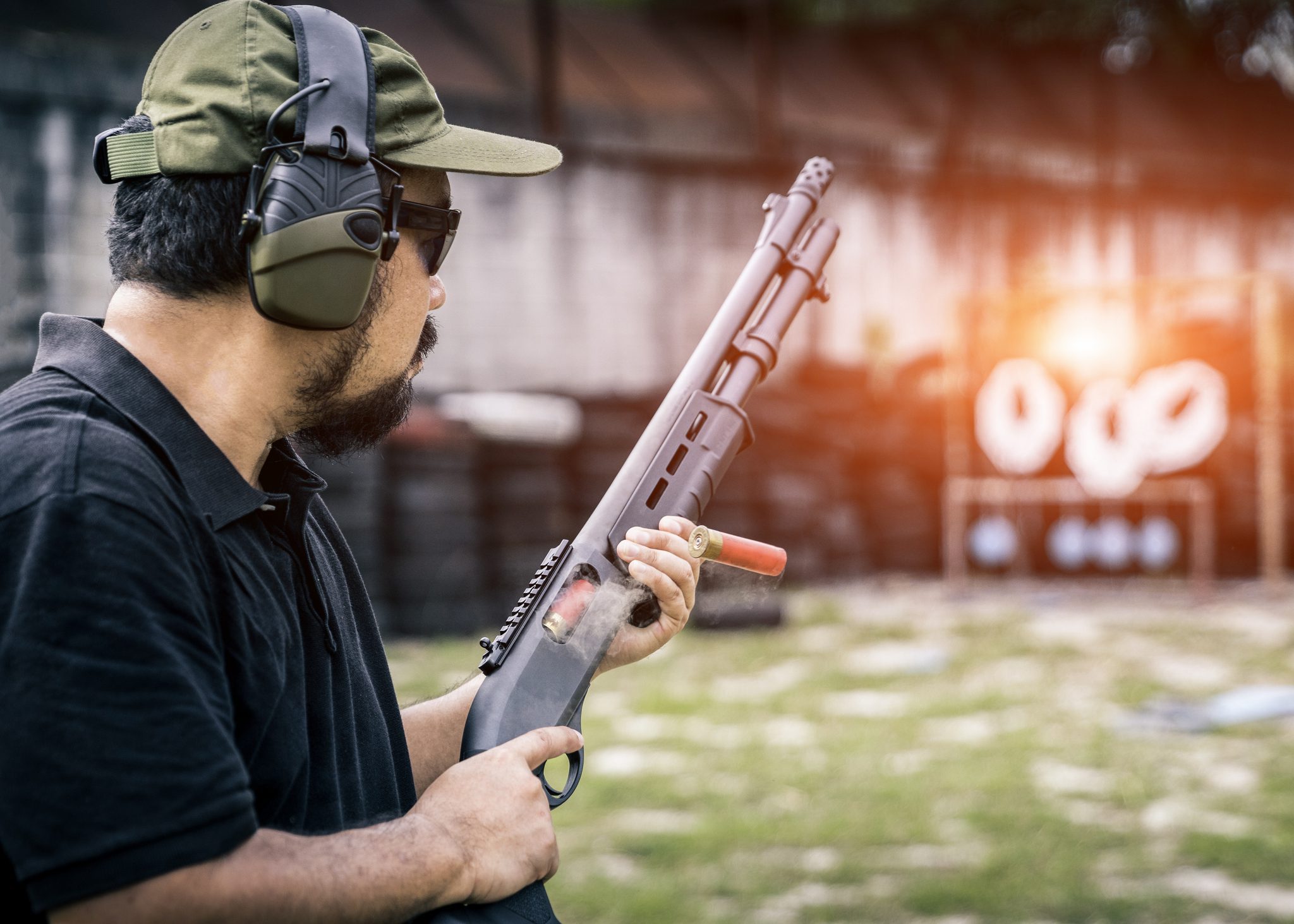 Man at shooting range holding a shotgun.